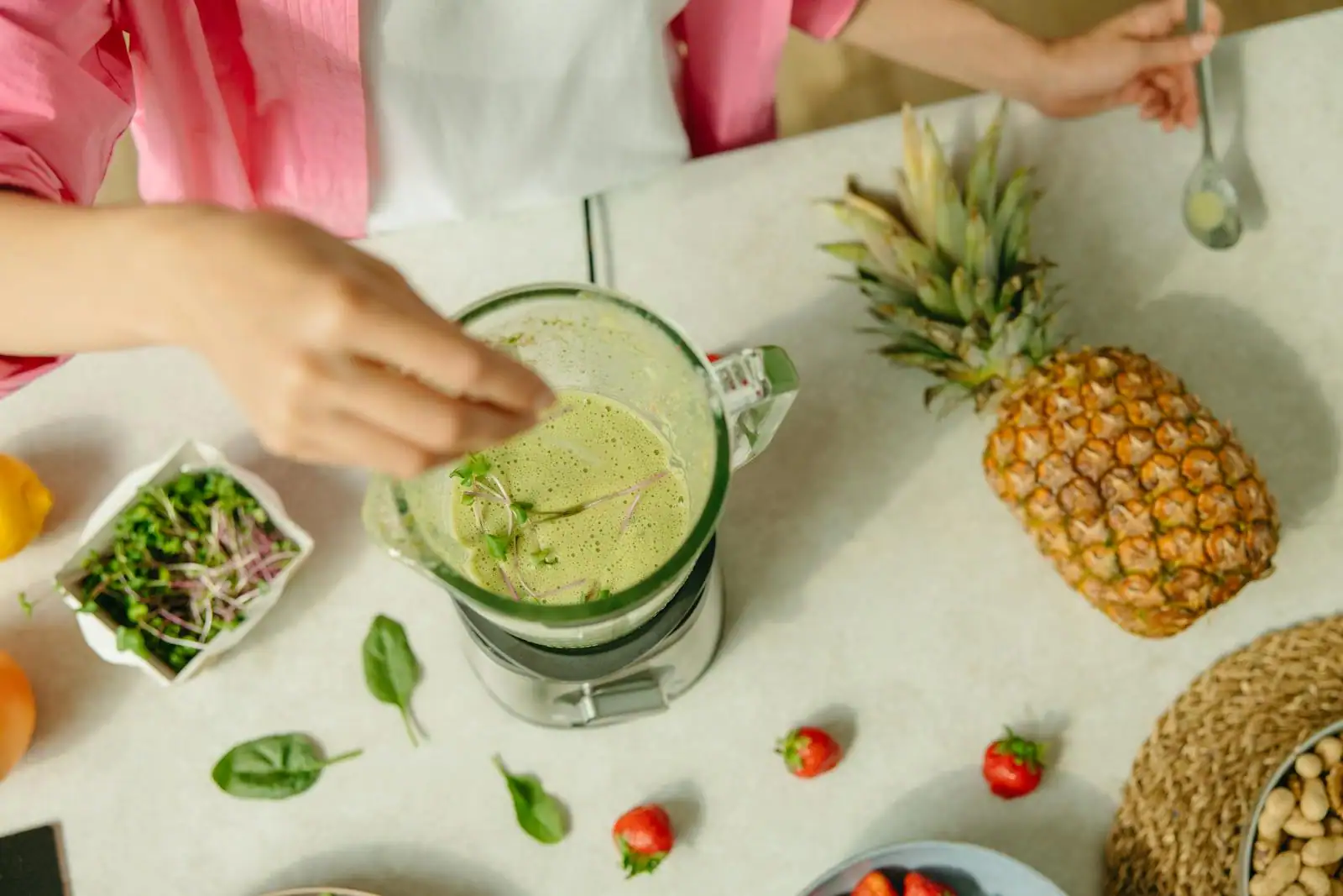 Blender posé sur un plan de travail de cuisine, bol rempli d'un smoothie vert