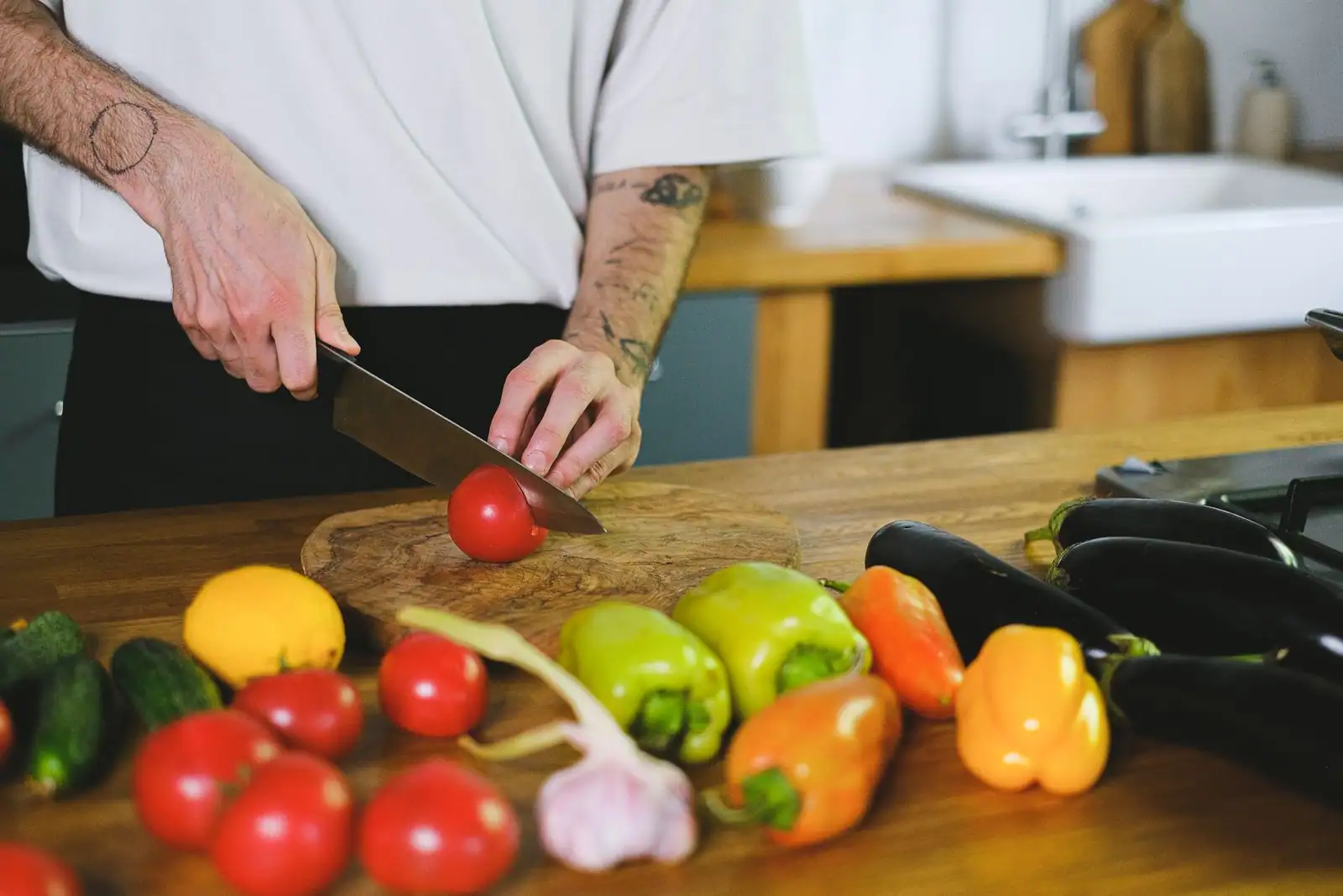 Couteau de chef posé sur une planche en bois avec des légumes émincés