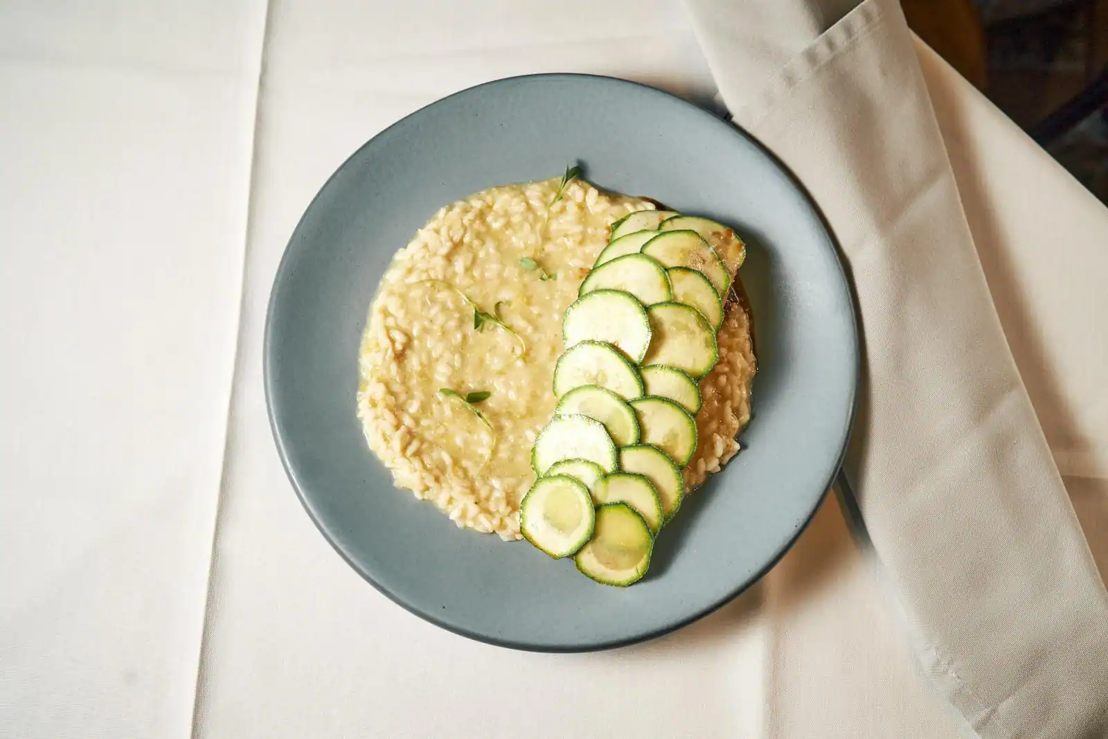 Assiette de risotto crémeux à la courgette parsemé de parmesan et de dés de courgette