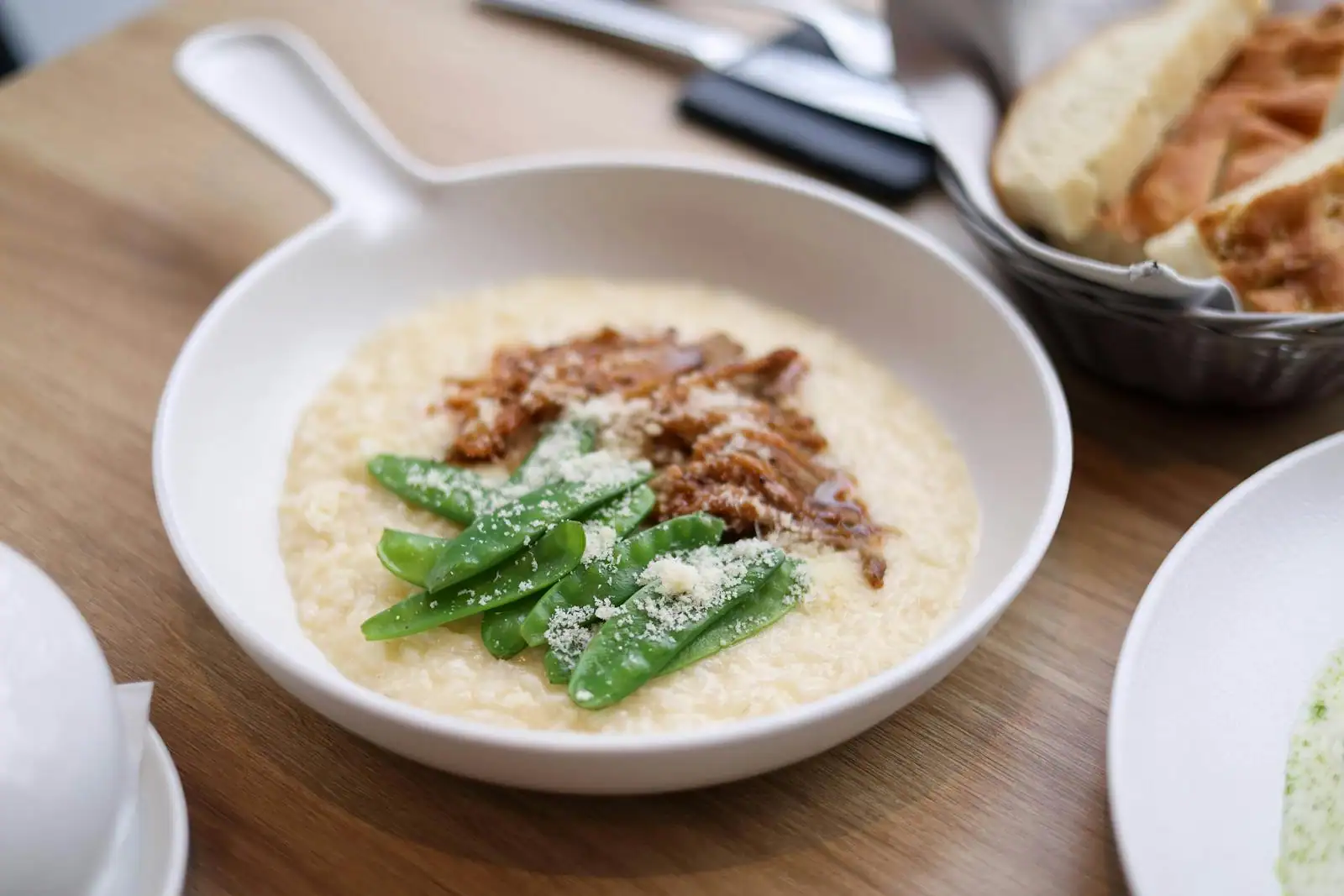 Assiette de risotto crémeux au parmesan fumant, servie sur une table en bois