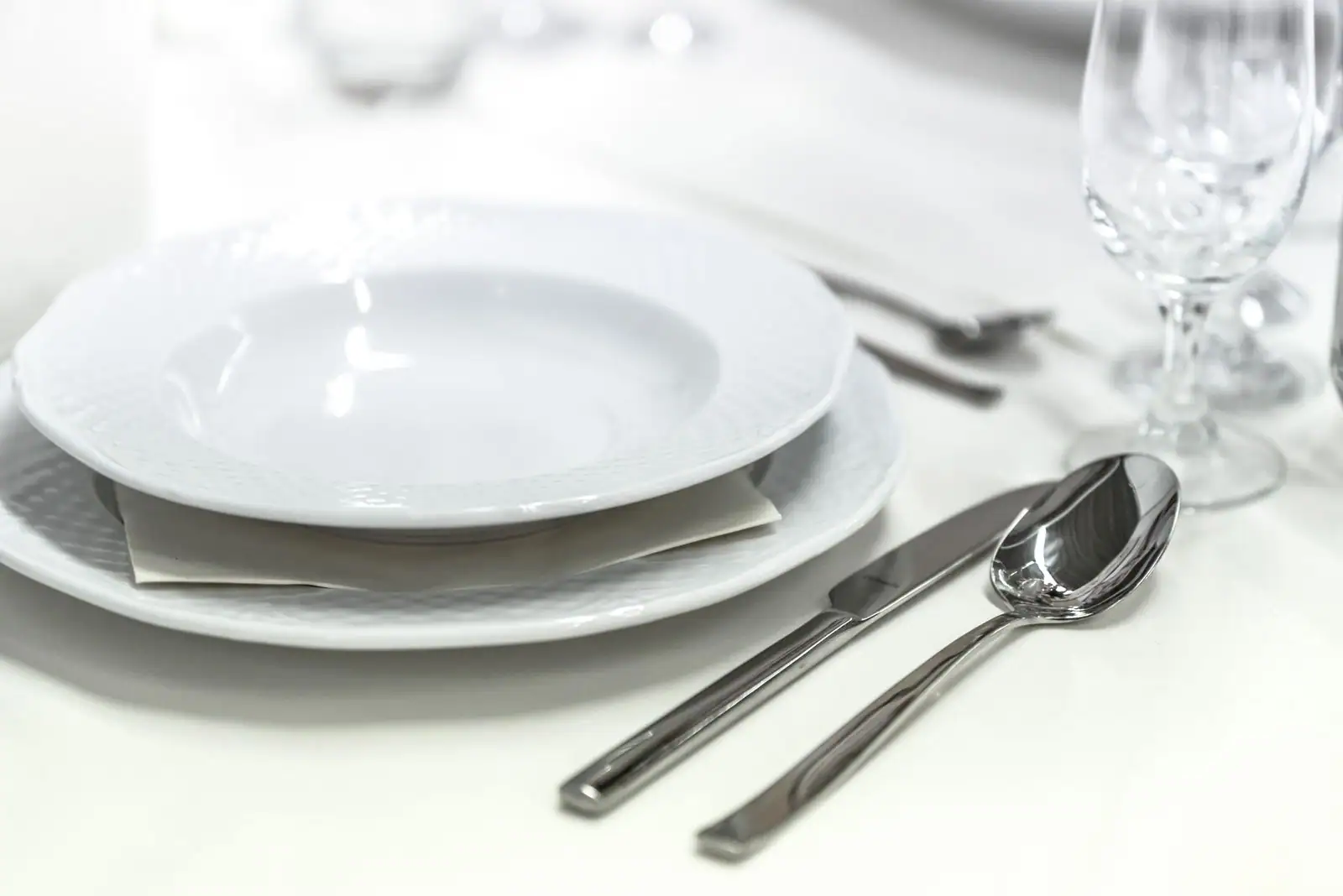 Service de table en porcelaine blanche dressé sur une nappe, assiettes empilées et plats de service