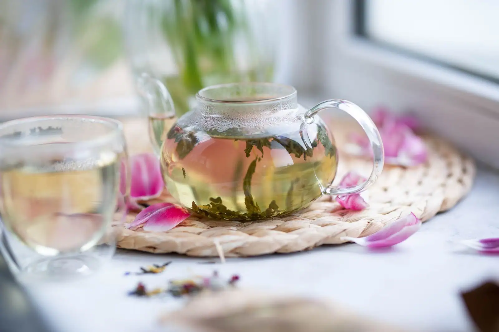 Tasse de thé fraîchement infusé à côté d'une théière et de feuilles de thé en vrac