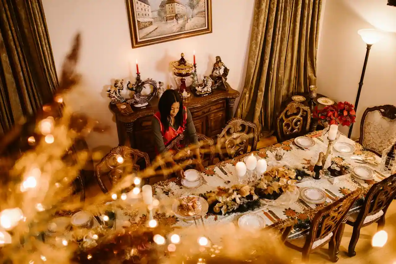 Table de Noël dressée avec vaisselle blanche, assiettes de présentation dorées, bougies et décor de sapin