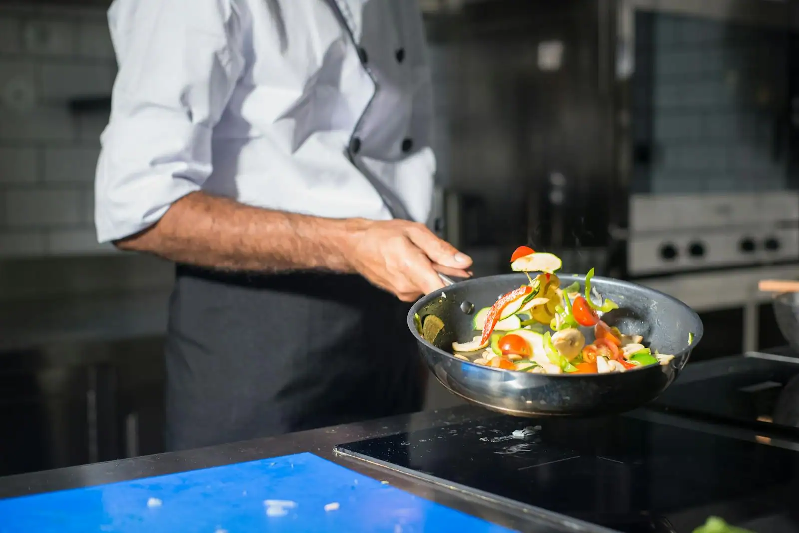 Légumes colorés sautés dans un wok en acier au-dessus d'une flamme vive