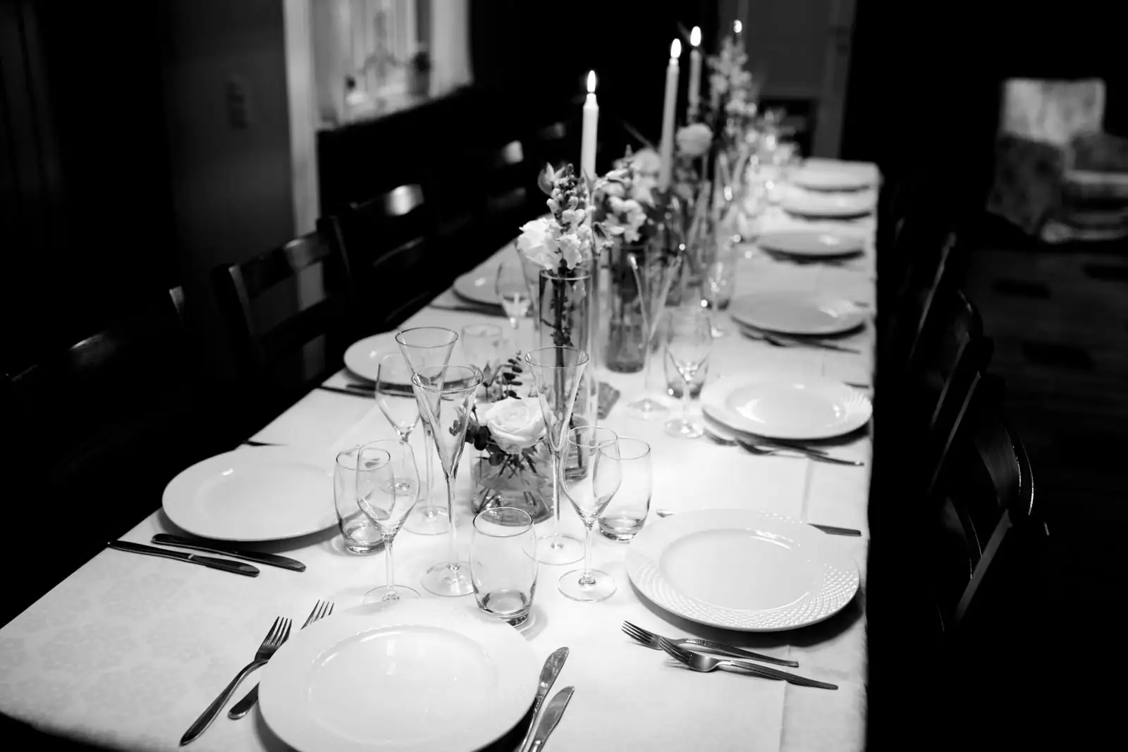 Longue table dressée avec assiettes, couverts, verres et bougies