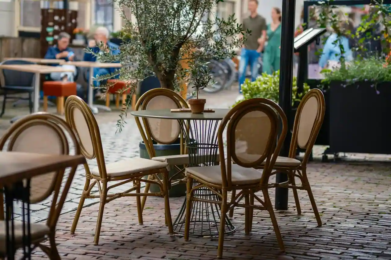 Terrasse d'un café-brasserie avec tables et chaises en rotin sur une rue pavée
