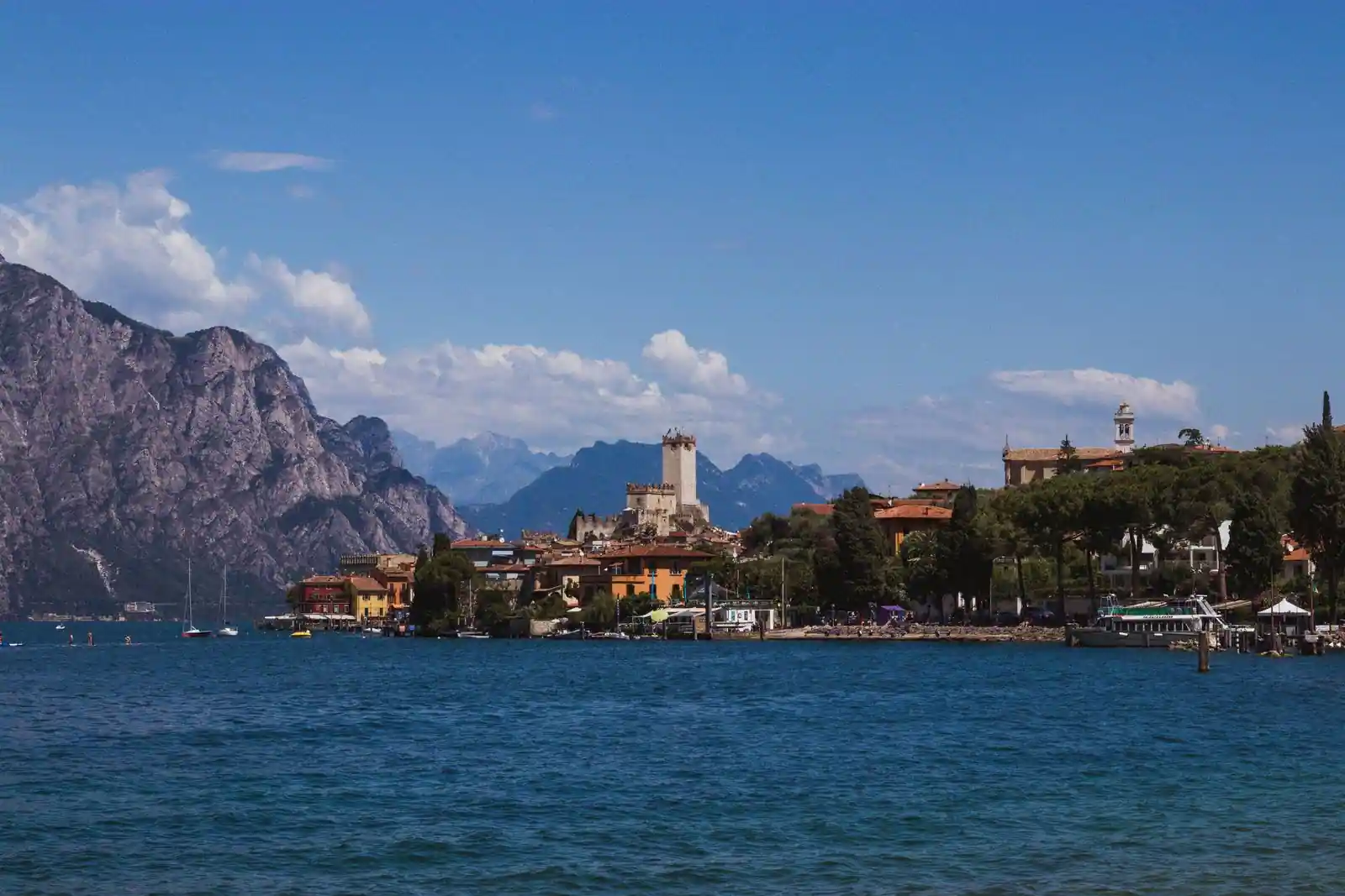 Vue du lac de Garde en Italie, village au bord de l'eau dominé par un château et montagnes en arrière-plan