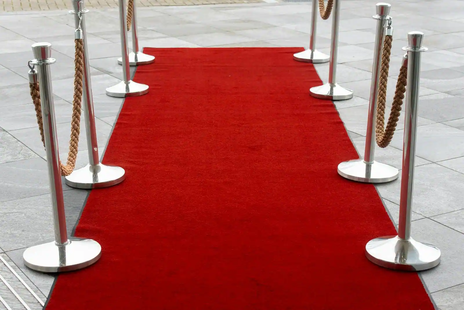 Tapis rouge bordé de poteaux à cordons menant à une entrée