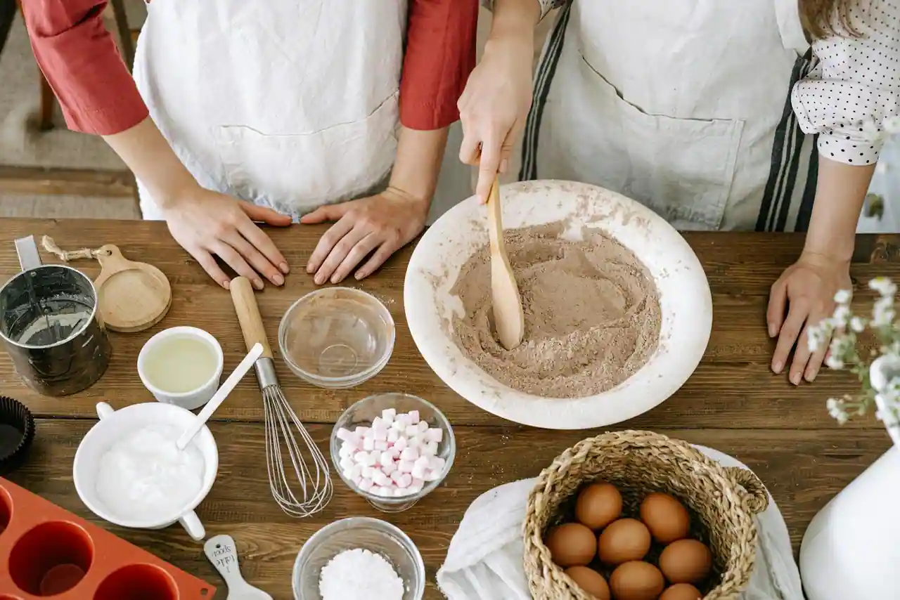 Vue de dessus d'une scène de pâtisserie : un bol de farine mélangée à la cuillère et des ingrédients