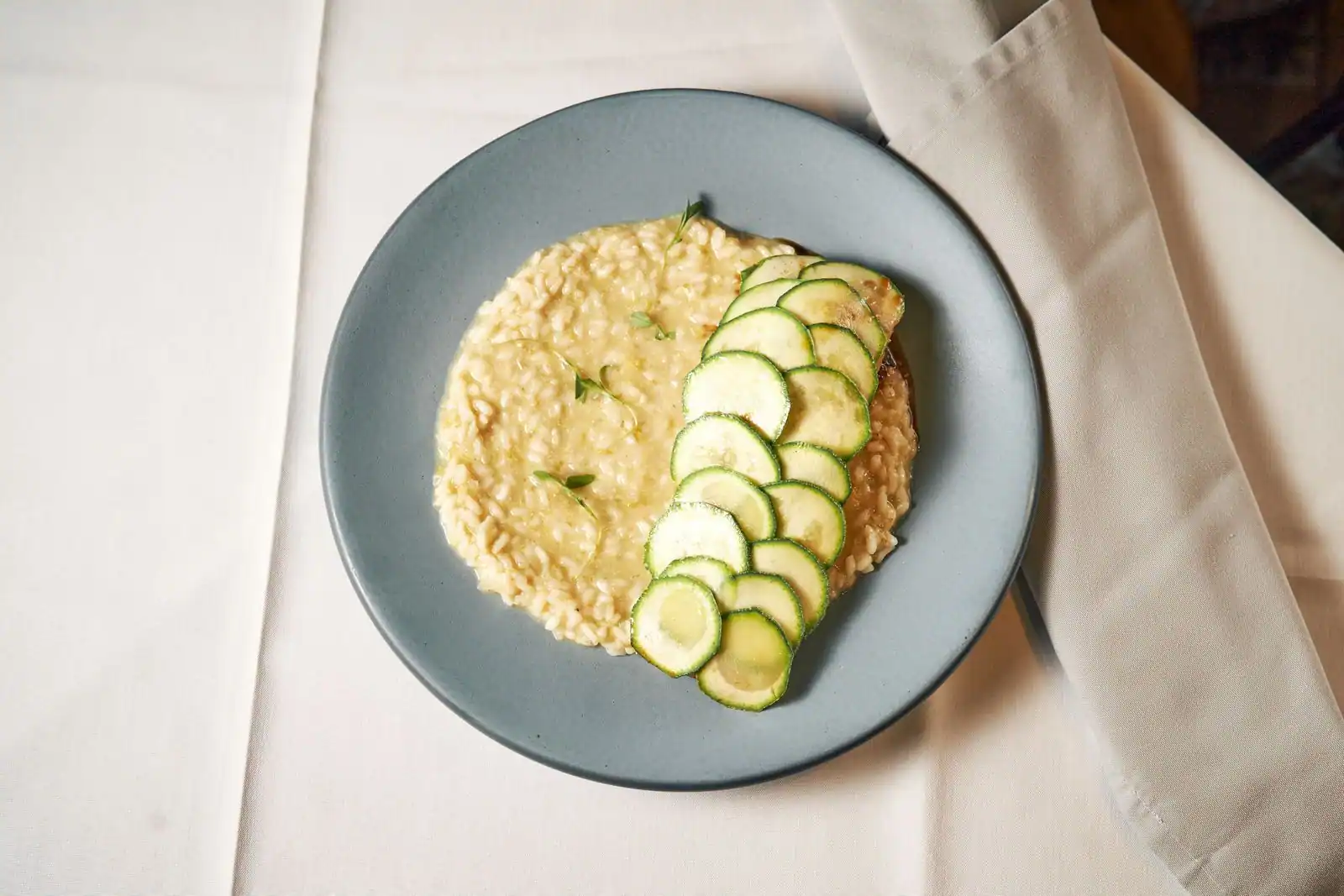 Assiette de risotto crémeux garni de fines rondelles de courgette