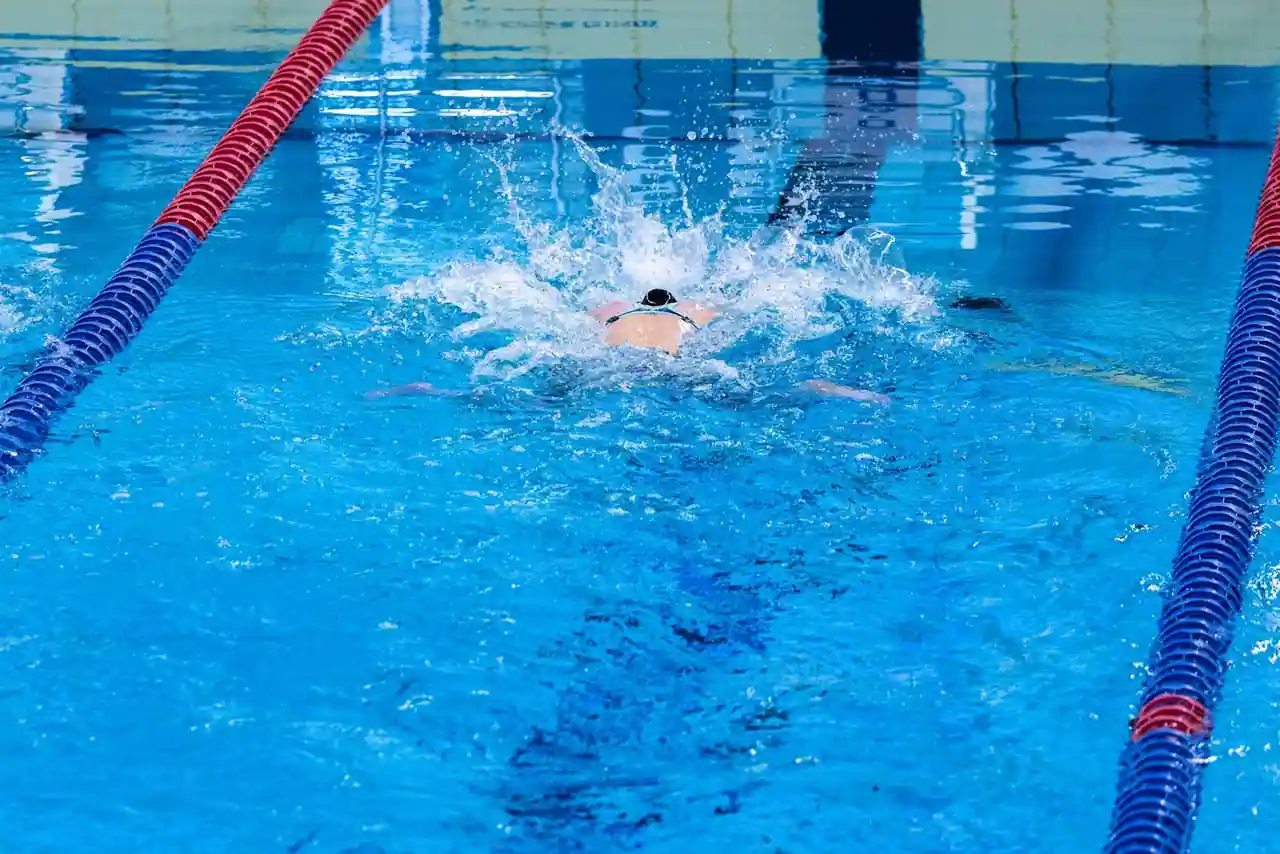 Nageur en plein effort dans un couloir de bassin de natation, eau bleue et lignes d'eau