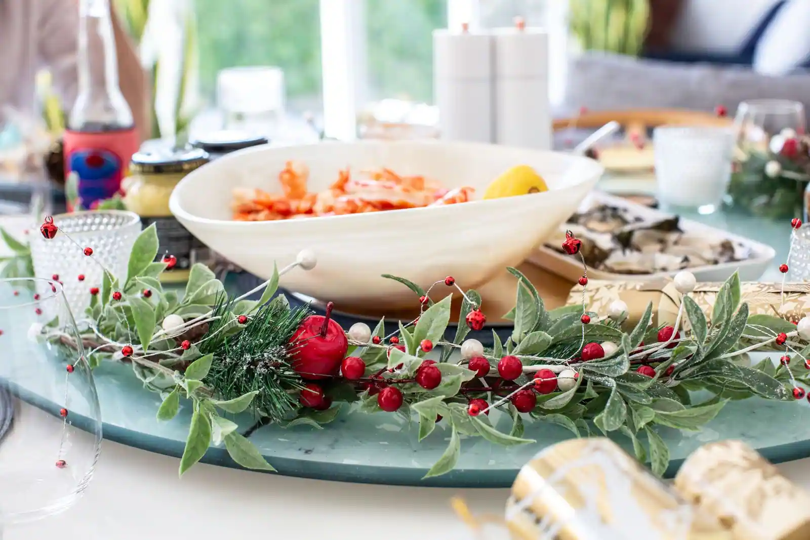 Coupe de crevettes et plateau d'huîtres sur une table de fête décorée d'une guirlande de baies rouges