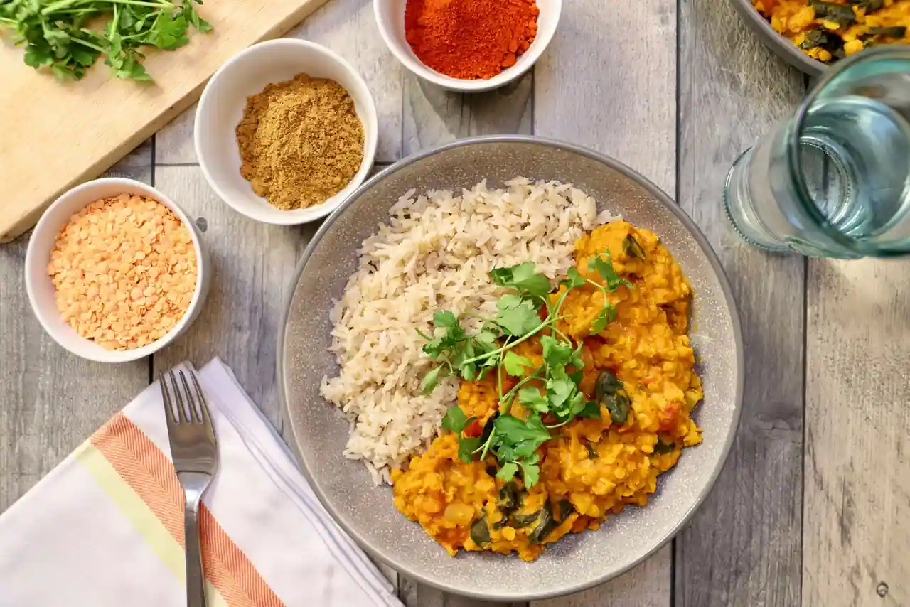 Bol de dal de lentilles corail aux épices, parsemé de coriandre fraîche et servi avec du riz