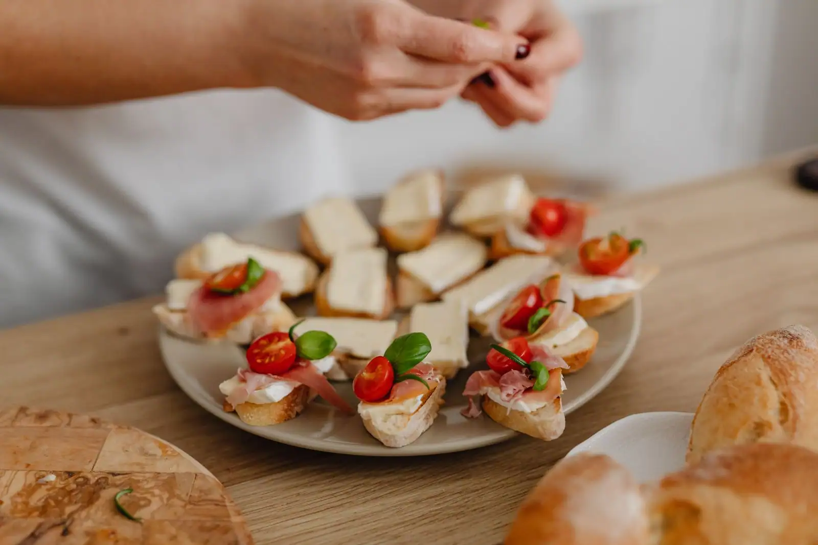 Petits toasts au fromage, jambon cru et tomates cerises dressés sur assiette, entrée simple.