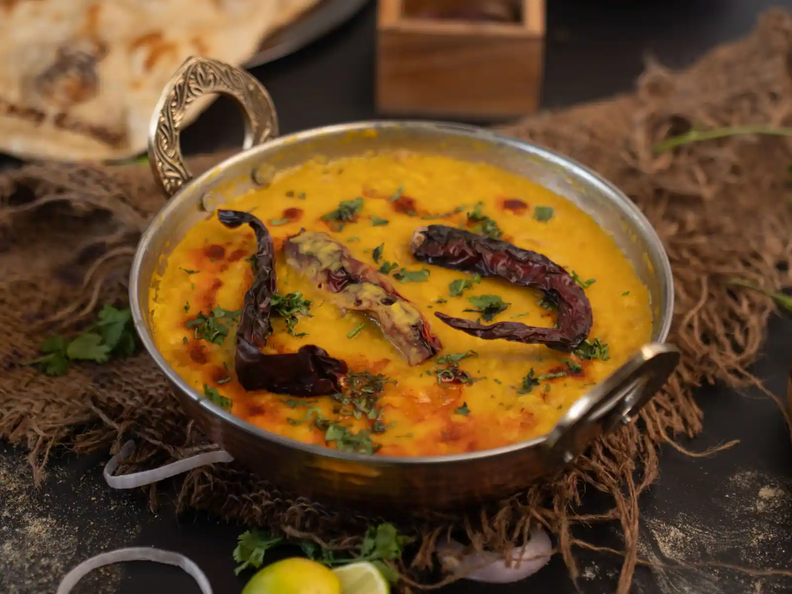 Curry de lentilles dans un kadai en métal, garni de piments secs et de coriandre fraîche.