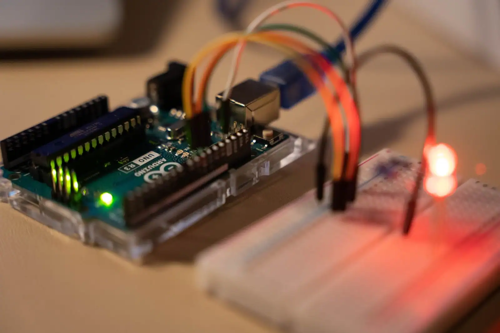 Carte Arduino Uno reliée à une breadboard par des fils de connexion, LED rouge allumée.